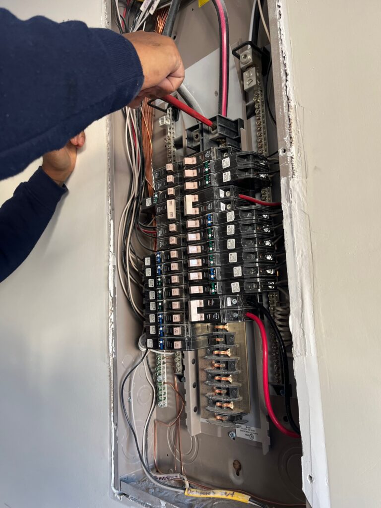 Electrician working inside a residential electrical panel during a panel upgrade